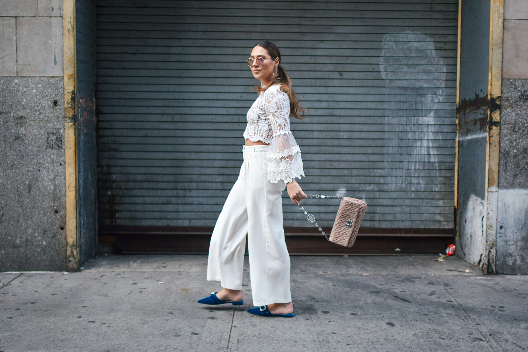 nyfw-streetstyle-outfit-lace-ruffle-statement-bell-sleeve-blouse-white-trousers-all-white-prada-royal-blue-slides-blush-accessories